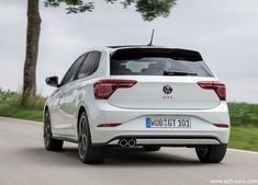 the rear end of a white vw polo estate car driving down a country road