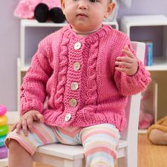 a baby sitting in a chair wearing a pink knitted sweater and matching striped pants