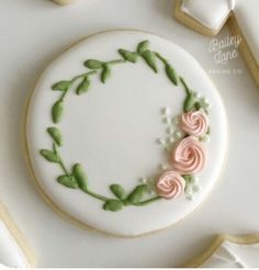 a decorated cookie with pink roses and green leaves