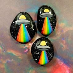 three space themed rocks with a rainbow in the middle