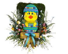 an easter decoration with a yellow chick in a blue knitted egg surrounded by greenery