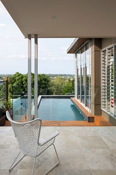 a chair sitting on top of a tiled floor next to a swimming pool in a house