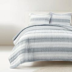 a bed with blue and white bedspread on top of it next to a rug