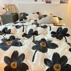 a bed with black flowers on it in a room next to a lamp and pictures