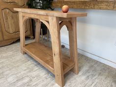 a wooden table with an apple sitting on it's shelf next to a mirror