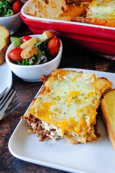 two plates with lasagna casserole, bread and salad on the table