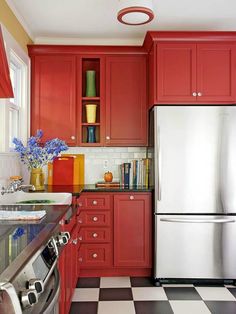 a kitchen with red cabinets and black and white checkered flooring, stainless steel appliances