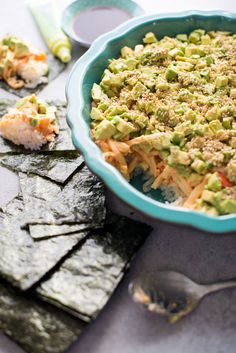 a bowl filled with food sitting on top of a table next to crackers and utensils