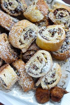 a white plate topped with lots of pastries covered in powdered sugar and nuts