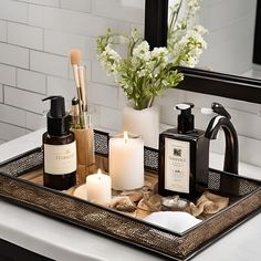 a tray with candles, soaps and other items on it in front of a mirror