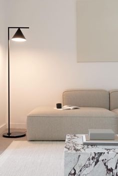 a living room with a couch, coffee table and lamp on the wall next to it