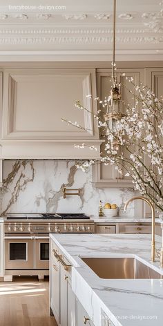 an elegant kitchen with marble counter tops and gold accents on the ceiling, along with white cabinets