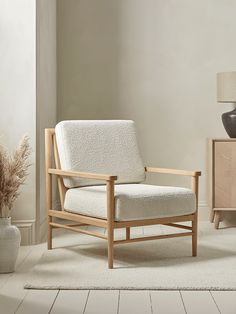 a living room with a chair, vase and lamp on the side table in front of it