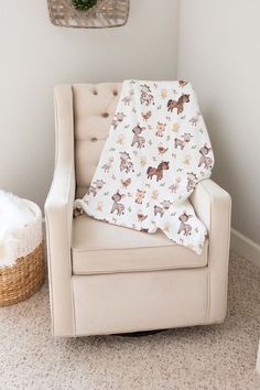 a chair with a blanket on it next to a basket and wall hanging in the corner