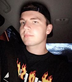 a man sitting in the back seat of a car wearing a black shirt with flames on it