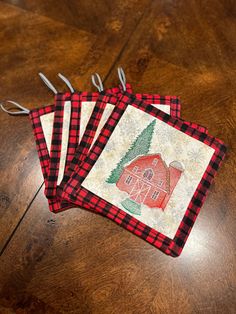 three red and black placemats sitting on top of a wooden table next to scissors