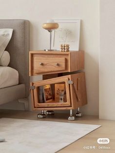 a wooden cabinet with two drawers on wheels in front of a bed and nightstand next to it