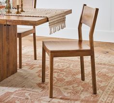 a dining room table with two chairs and a rug on the floor