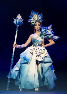 a woman in a blue and white dress holding a stick on top of a stage