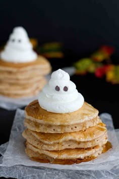 a stack of pancakes topped with whipped cream and ghost faces on top of each other