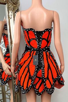 This Sweet embrace dress features a bold butterfly wing design, predominantly in vibrant orange and black, adorned with shimmering sequins that catch the light beautifully. The dress has a form-fitting silhouette that accentuates the waist and hips, with a hemline cut to resemble the natural curves of a butterfly wing. The edges of the wings are outlined with pearl-like beads, adding an element of elegance and sophistication. This unique dress is perfect for making a statement at any event, comb Orange Butterfly Dress, Butterfly Wing Dress Gowns, 3d Butterfly Applique Dress, Butterfly Couture Dress, Monarch Butterfly Dress, Butterfly Wing Design, Bandage Top, Wing Design, Unique Dress