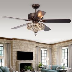 a living room filled with furniture and a ceiling fan mounted to the side of a stone wall