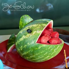 a watermelon shaped like a fish with its mouth open and some strawberries in it