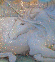 a white horse laying on top of a bed covered in glitter