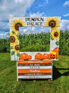 a wooden sign with sunflowers and pumpkins painted on it in the grass