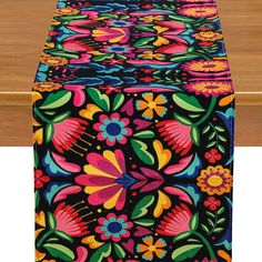 an image of a colorful table runner on a wooden table with flowers and leaves painted on it