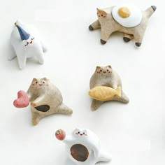 five ceramic cats with eggs on their heads and one in the shape of a cat