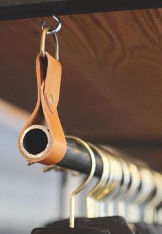 a pair of scissors hanging from the side of a rack with leather handles on it