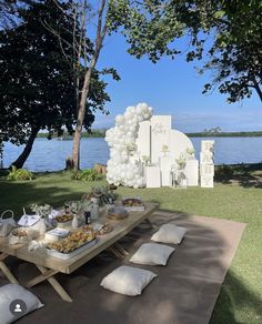 a picnic table with white balloons and food on it