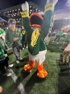 a mascot is standing in the middle of a football field with his arms up and legs spread out