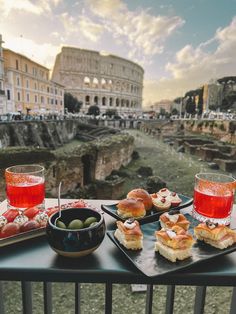 some food is sitting on a table with drinks and water in front of the river