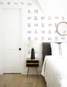 a white bedroom with black and white wallpaper