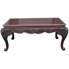 an ornate coffee table with glass top and carved wood frame on the legs, against a white background