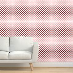 a white couch sitting in front of a wall with red polka dot designs on it