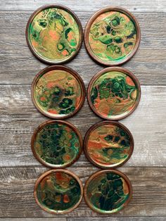 six green and gold coasters sitting on top of a wooden table next to each other