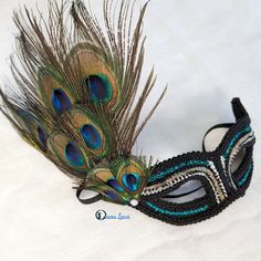 Black fabric masquerade mask decorated with silver and black trims and teal holographic glitter. Peacock feathers decorate one side of the mask. Plastic base covered with fabric on both sides for comfort. Hand made in Australia. elastic ties. Laura Lucci Collection. NOTE: Shipment is via Australia Post, check their website at: https://auspost.com.au for estimated delivery times to your location. Peacock Masquerade, Masquerade Mask Black, Black Peacock, Mask Black, Australia Post, Costume Mask, Masquerade Mask, Peacock Feathers, Holographic Glitter