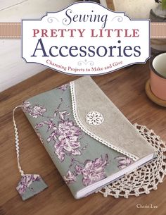 the cover of sewing pretty little accessories on a wooden table with a cup and saucer