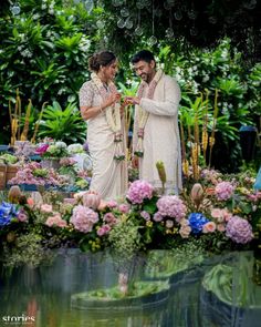 two people standing next to each other in front of flowers