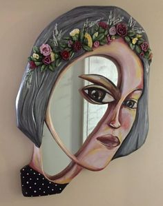 a woman's face painted on the side of a mirror with flowers in her hair