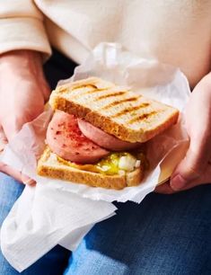 a person holding a sandwich with meat and pickles on it's side in their hands