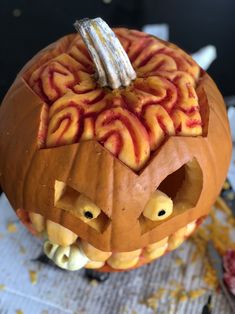 a carved pumpkin with an evil face and spirals on it's side, sitting on a table