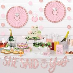 a table topped with lots of desserts and drinks next to a wall covered in pink polka dots