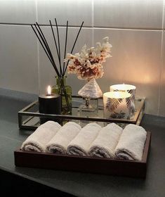 a tray with candles, flowers and towels on top of a table next to a vase