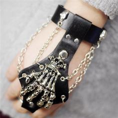 Looking for a little fantasy? This skeleton hand bracelet, both morbid and elegant, will fit you like a glove! This gothic punk bracelet was made and designed for people fond of that unique and mysterious style. The leather is completely black, but the parts in steel are mostly in silver except for some details that are in black. In addition to that, you can see that the ring on the front is made to go in the middle finger, and the fingers in steel are pretty well detailed with small skull heads Skeleton Hand Bracelet, Punk Bracelets, Hand Bracelet With Ring, Rock Clothing, Gothic Skeleton, Steampunk Bracelet, Finger Bracelets, Clothing Aesthetic, Skeleton Skull