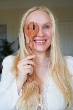 a woman holding up a wooden spoon with an odd shaped object in front of her face