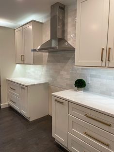 a kitchen with white cabinets and an oven in the center, surrounded by wood flooring